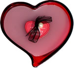 White candle in red heart-shaped glass dish