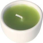 Single green candle in white ceramic cup 